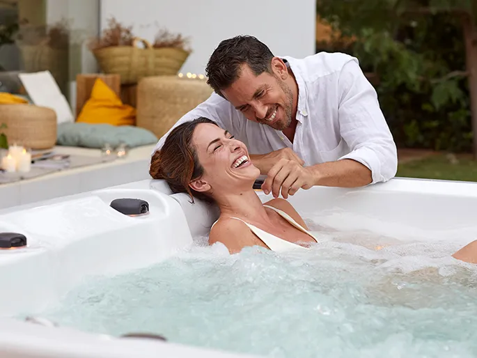 Szczęśliwa para relaksująca się w ogrodowej wannie z hydromasażem.