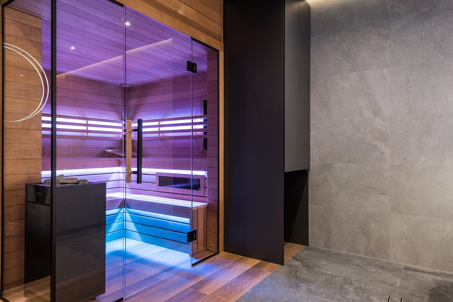 Nowoczesna domowa sauna z drewnianym wnętrzem i fioletowym oświetleniem LED.