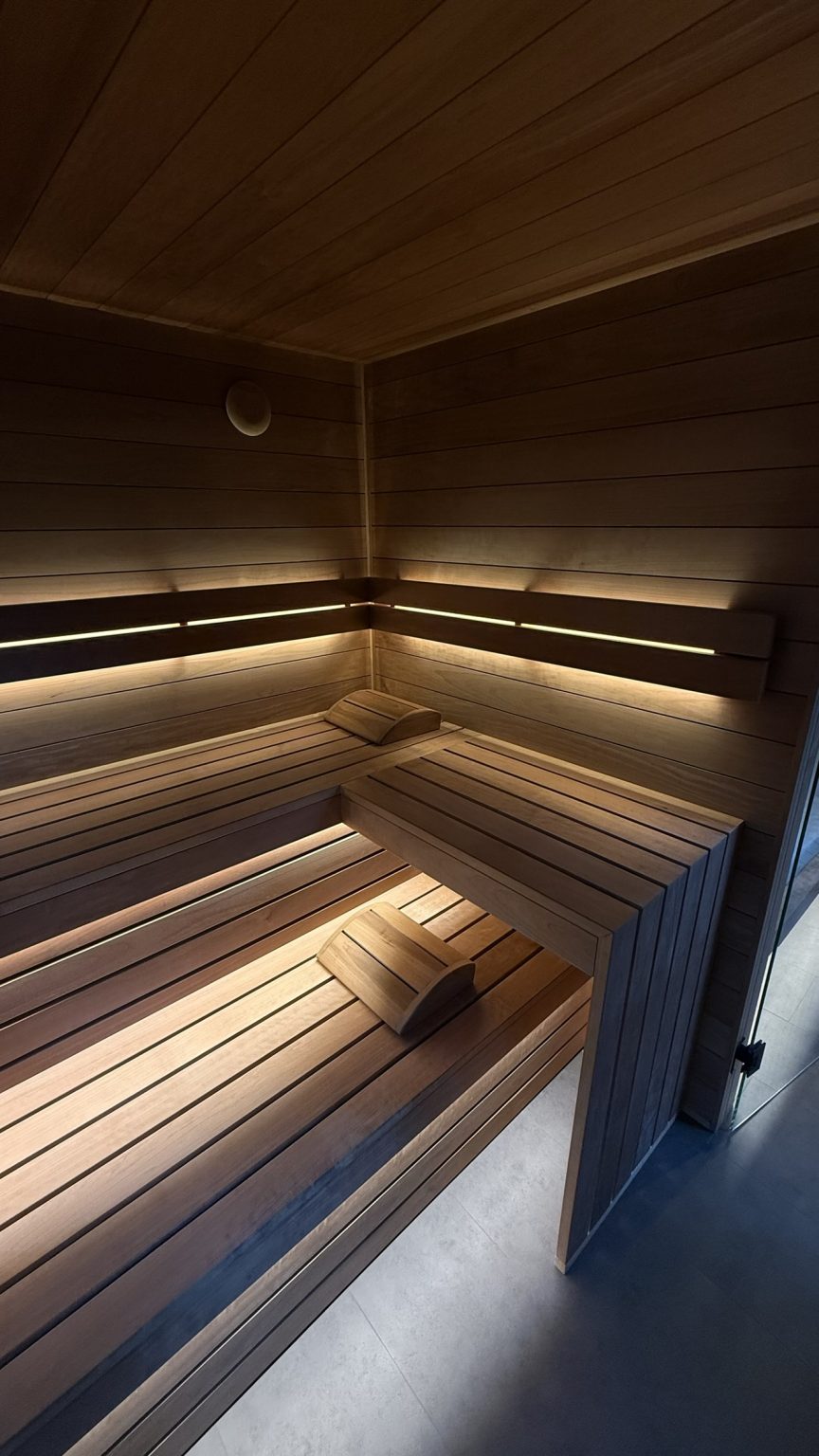 Wnętrze nowoczesnej sauny z drewnianymi ławami i nastrojowym podświetleniem LED.
