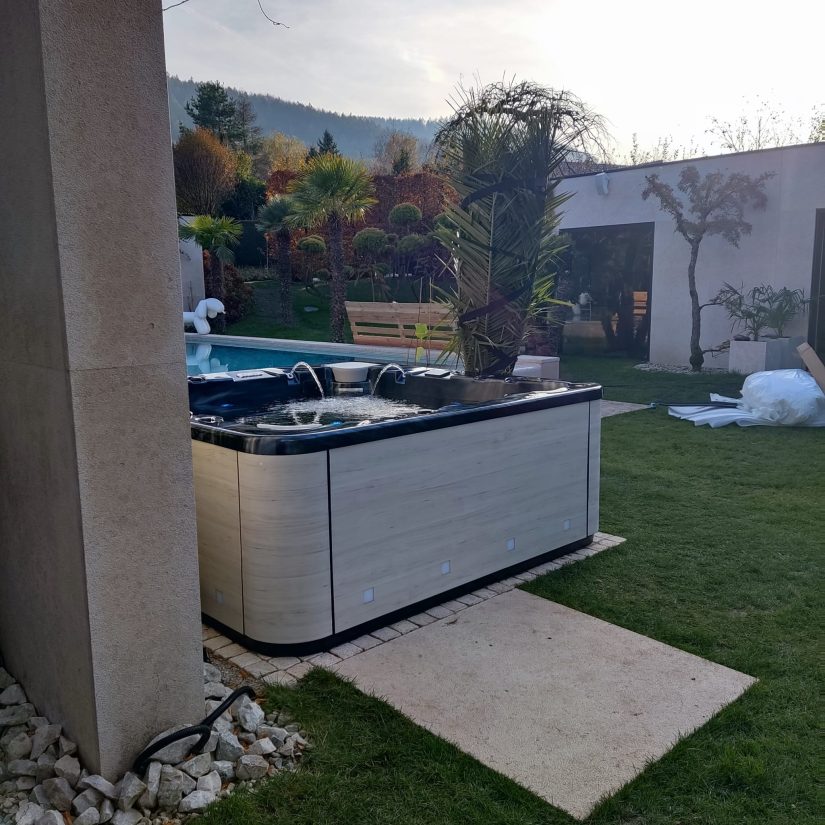 Nowoczesne jacuzzi w ogrodzie z basenem w tle.