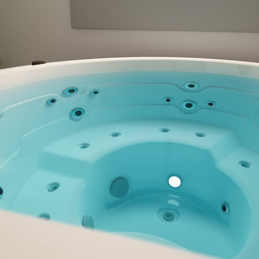 Wnętrze nowoczesnej wanny z hydromasażem wypełnionej błękitną wodą.