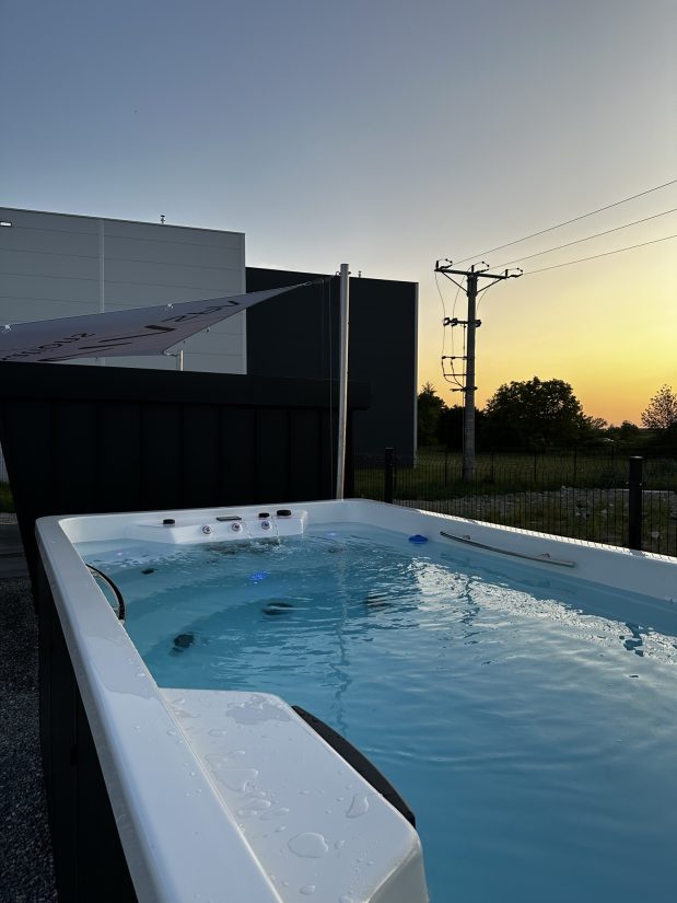 Zewnętrzne jacuzzi z podświetlaną wodą o zachodzie słońca.