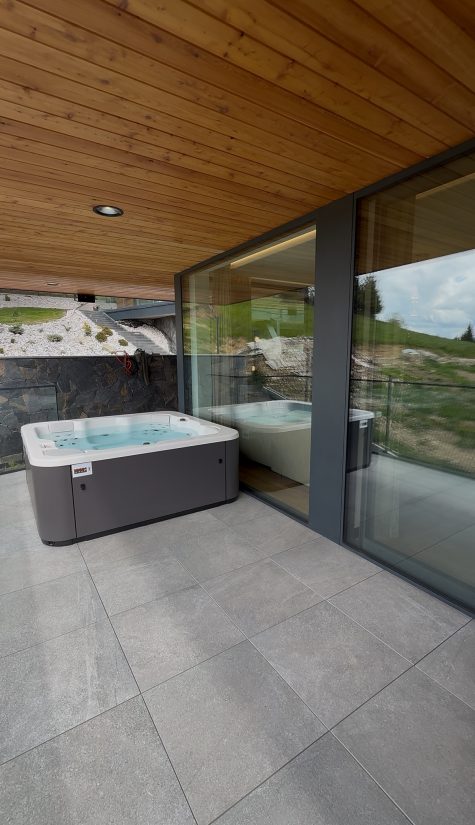 Nowoczesna wanna spa z hydromasażem na tarasie domu z widokiem na wzgórza.