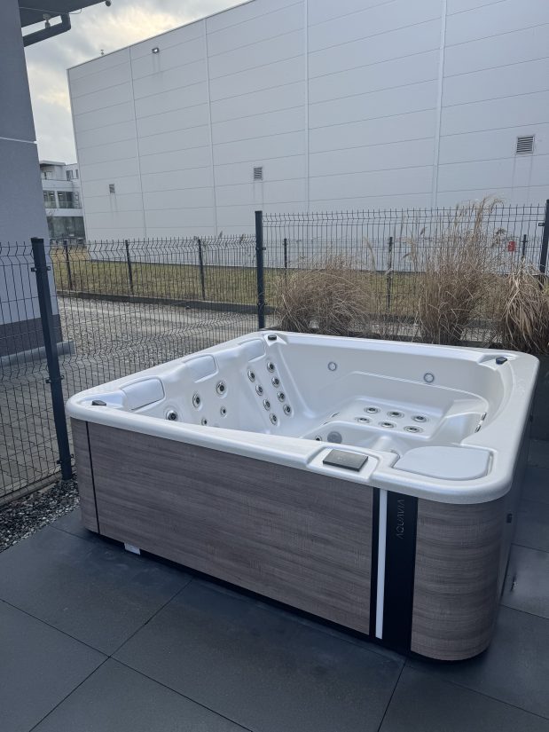 Wanna spa marki Aquavia ustawiona na tarasie przy ogrodzeniu.