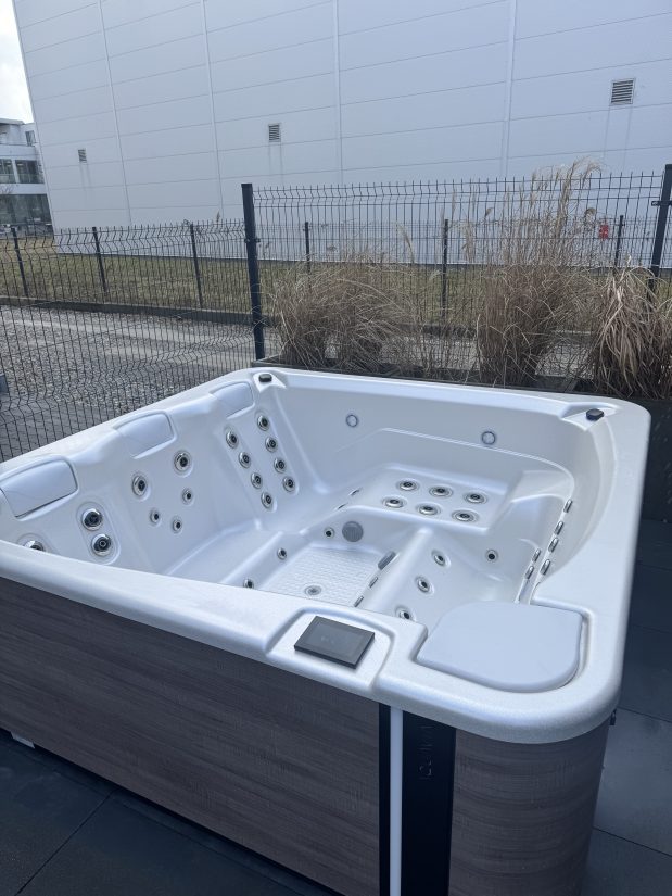 Biała wanna spa z hydromasażem na zewnątrz budynku.