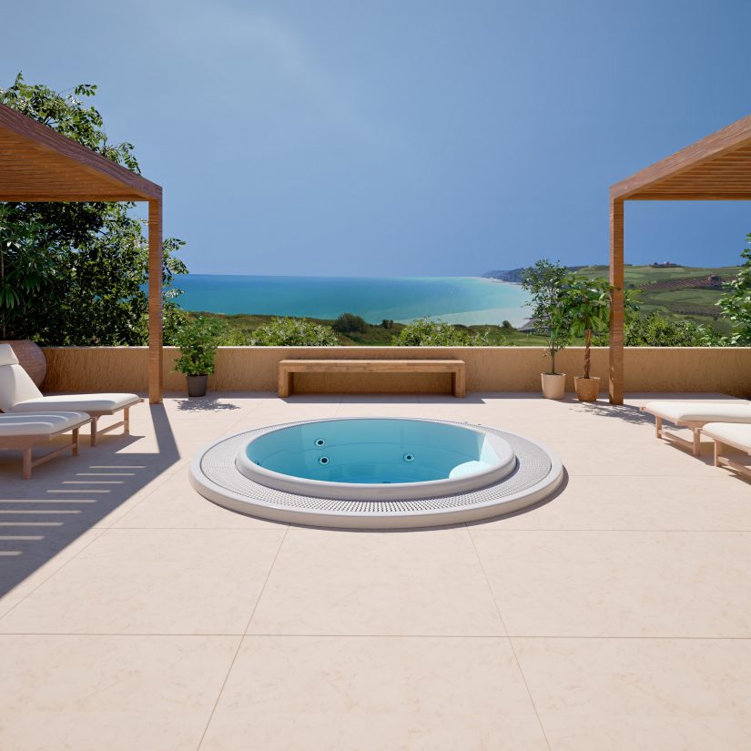 Okrągłe jacuzzi na tarasie z widokiem na morze i leżakami pod drewnianą pergolą.