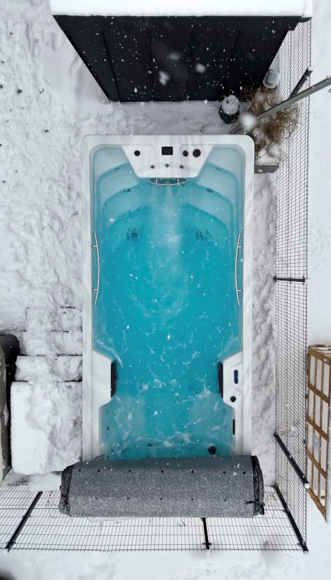Widok z góry na jacuzzi w ogrodzie zimą, podczas opadów śniegu.