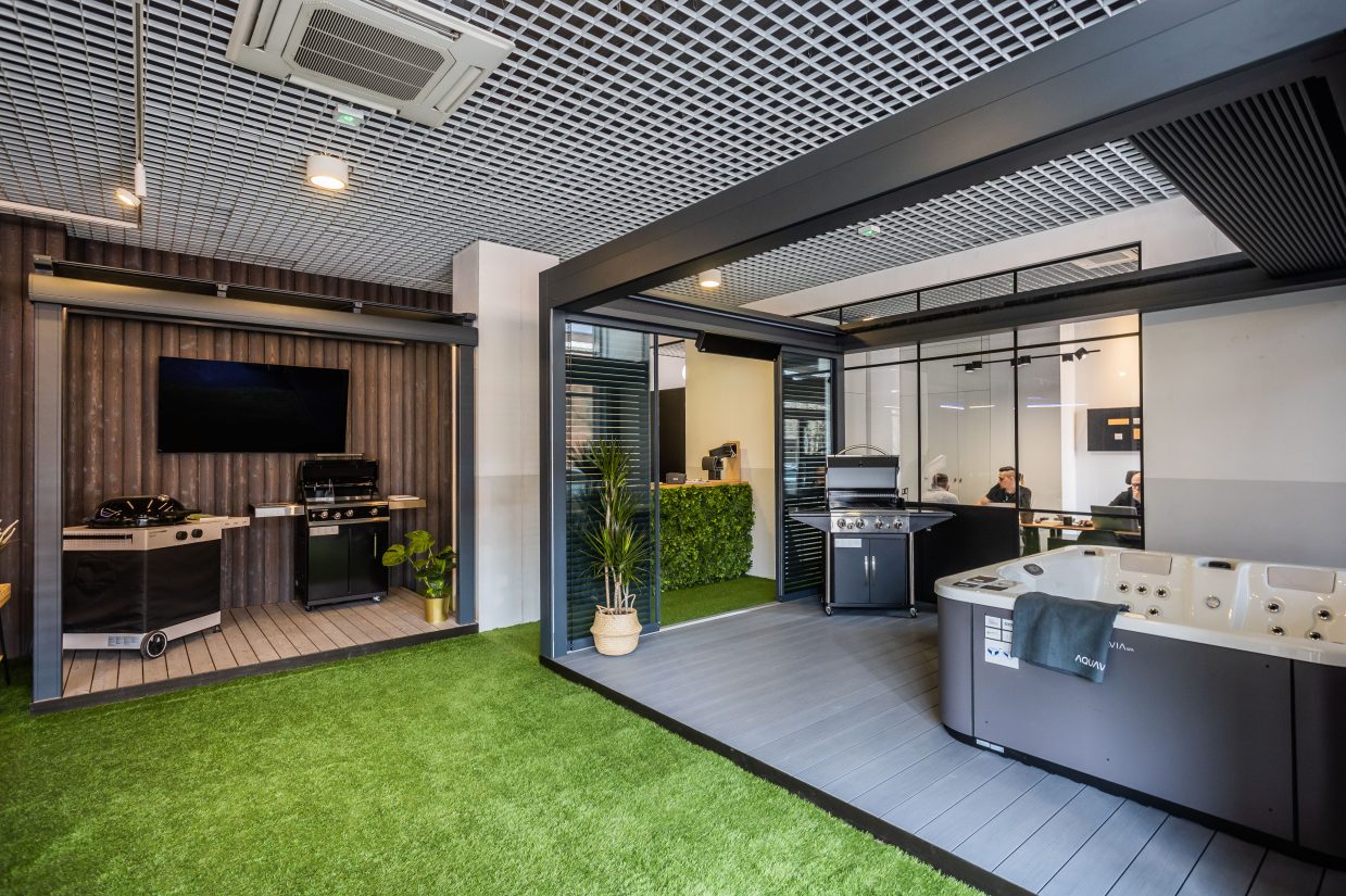 Wnętrze salonu z ekspozycją grilli ogrodowych, jacuzzi oraz tarasowych systemów zadaszeń.