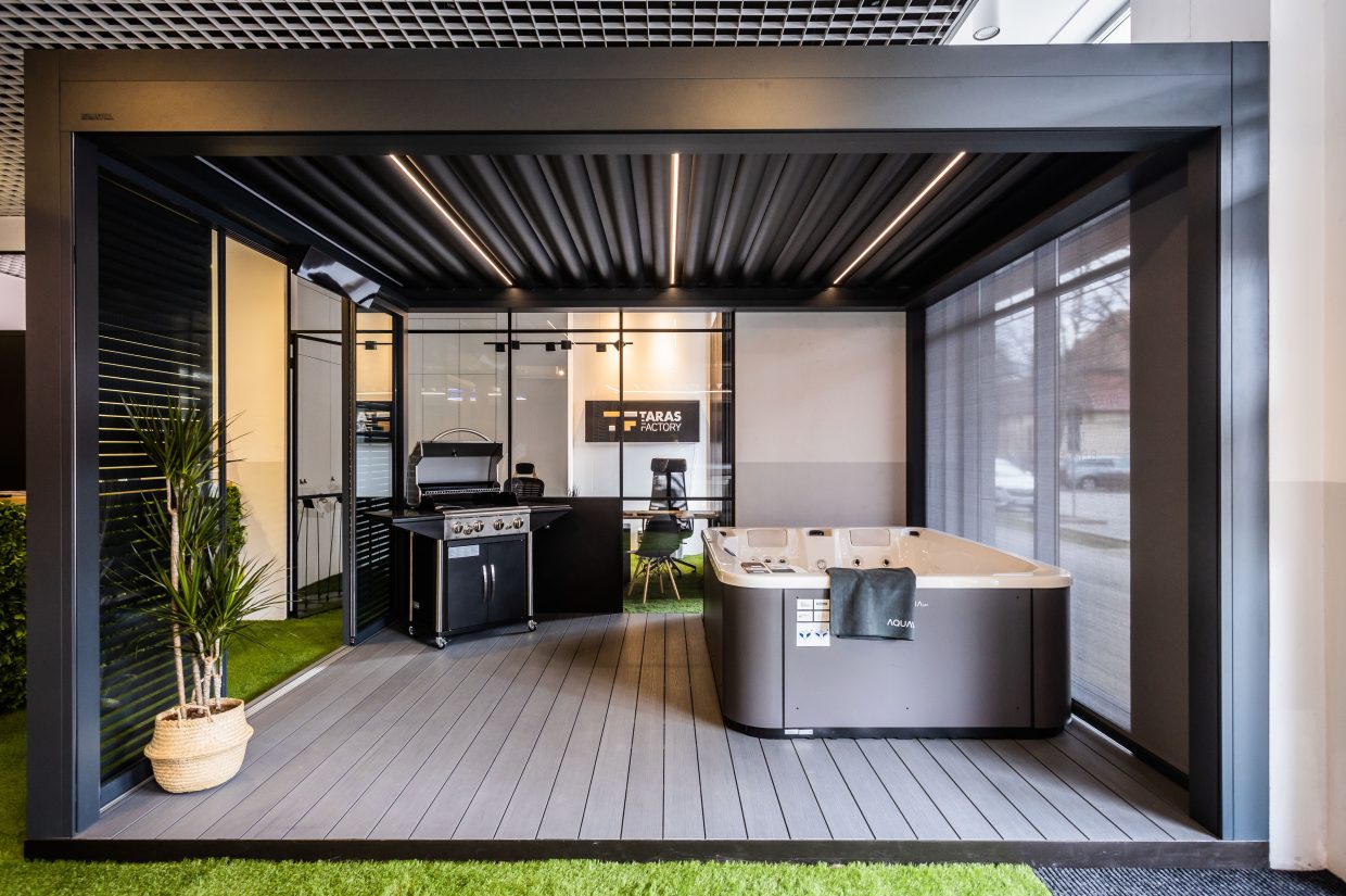 Nowoczesna pergola tarasowa z grillem gazowym i wanną spa w salonie wystawowym Taras Factory.