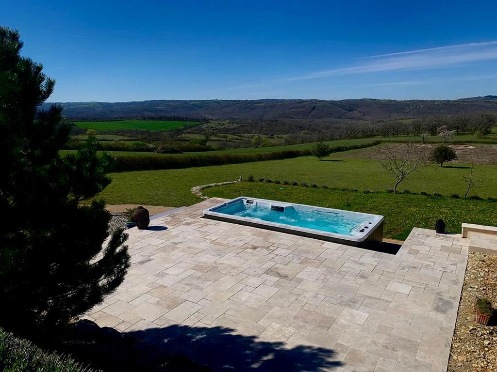 Wanna z hydromasażem na tarasie z widokiem na zielone wzgórza w słoneczny dzień.