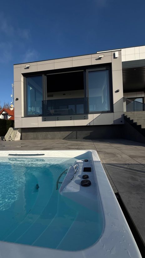 Nowoczesny dom z tarasem i jacuzzi w słoneczny dzień.