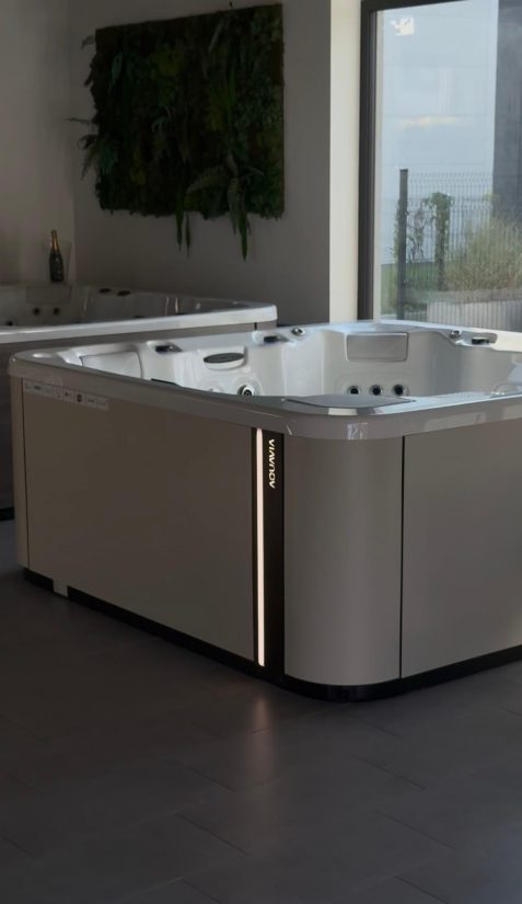 Nowoczesna wanna spa Aquavia z podświetlanym panelem bocznym w salonie wystawowym.