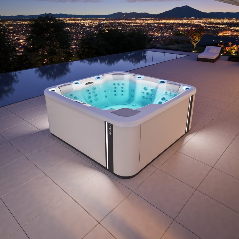 Podświetlane jacuzzi marki Aquavia na tarasie z widokiem na panoramę miasta nocą.