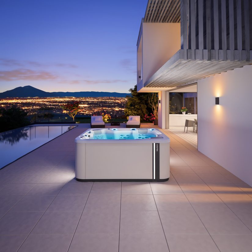 Podświetlane jacuzzi Aquavia na tarasie nowoczesnego domu z widokiem na oświetlone miasto wieczorem.