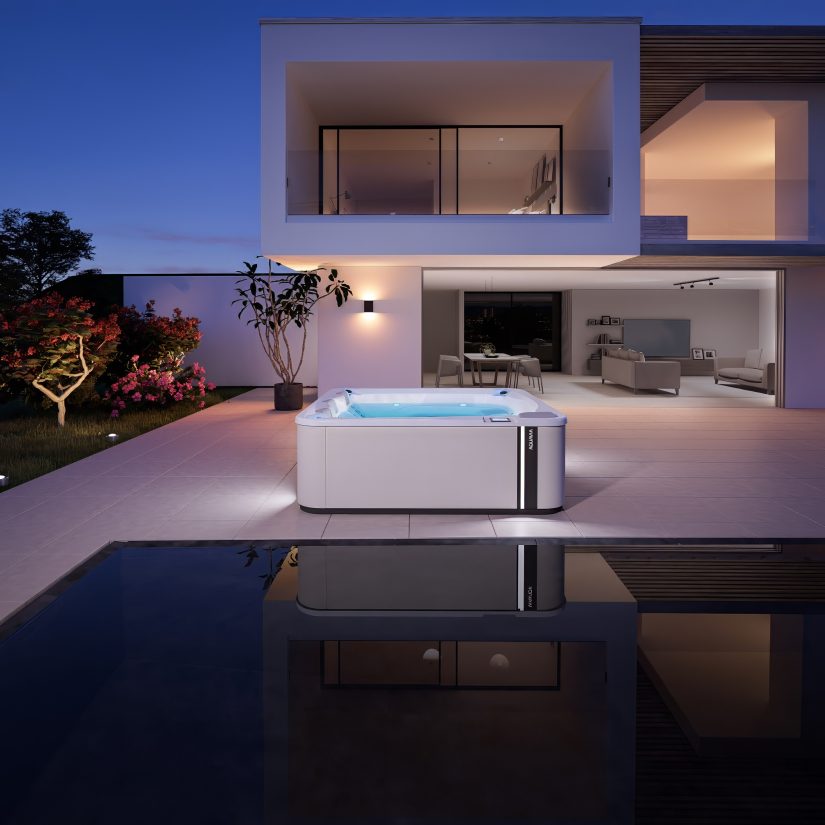 Wanna z hydromasażem Aquavia na nowoczesnym tarasie przy oświetlonym domu wieczorem.