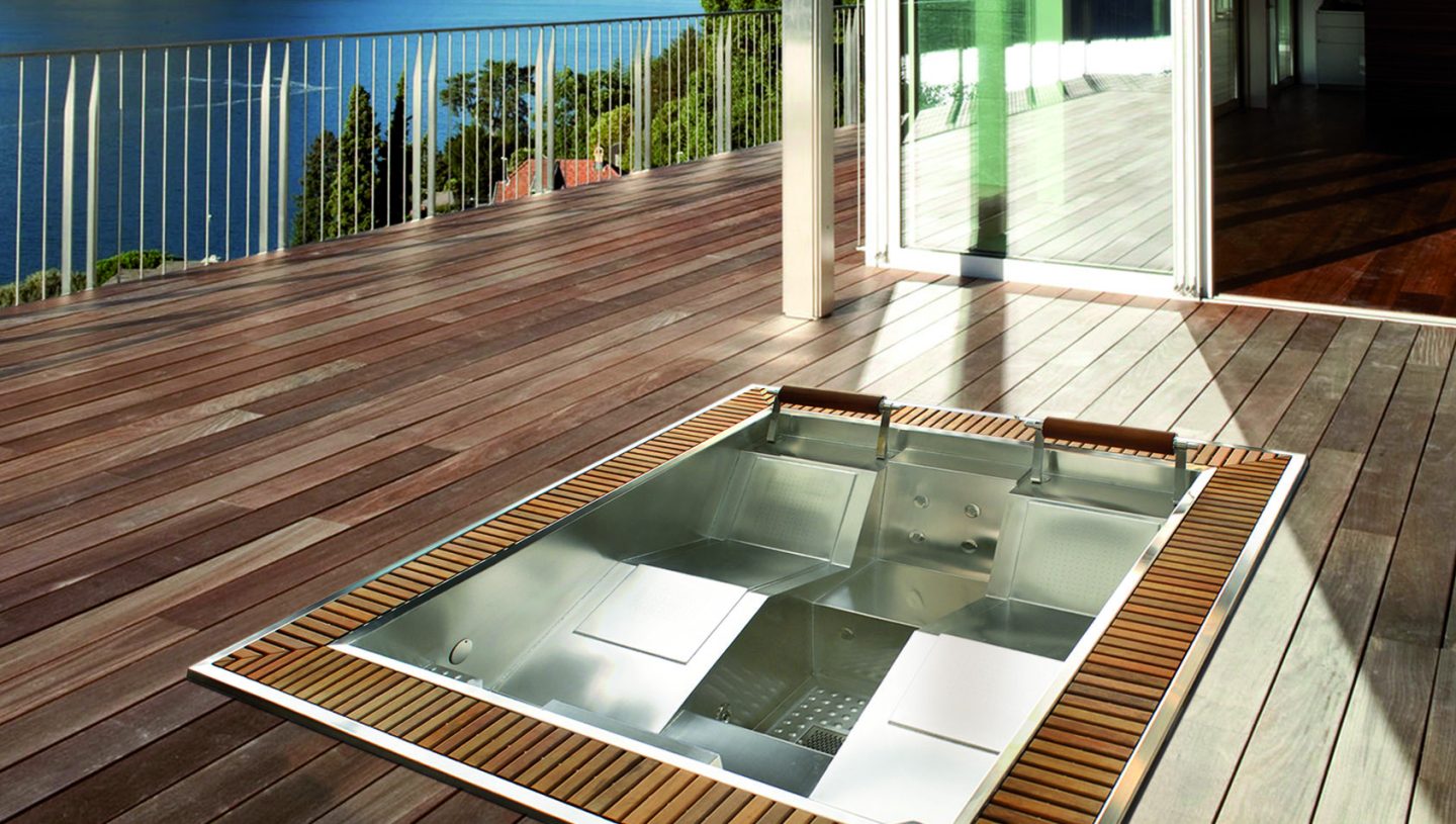 Wbudowana wanna z hydromasażem na drewnianym tarasie z widokiem na jezioro.