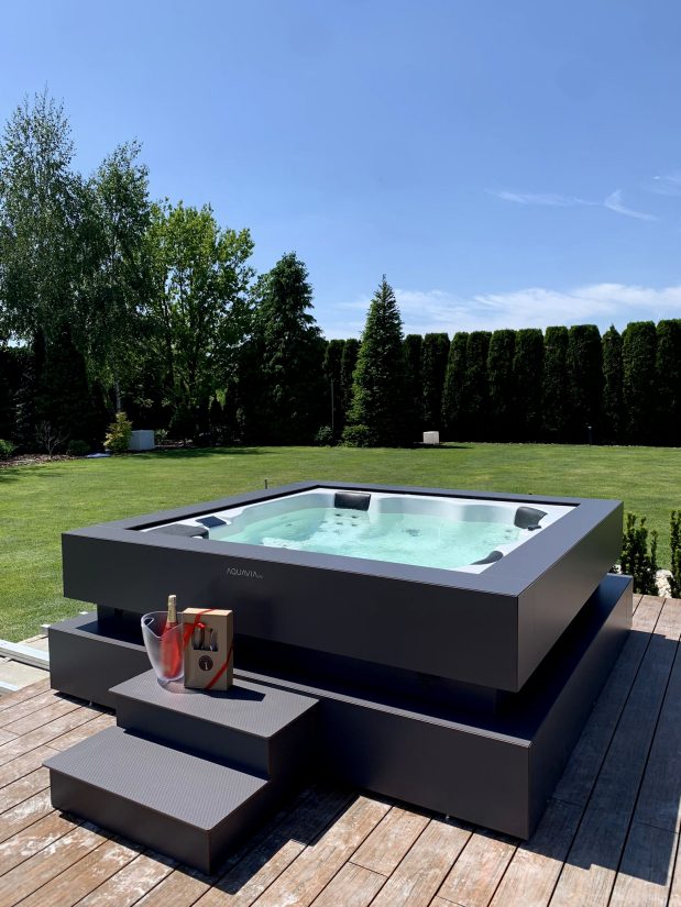 Wanna zewnętrzna Aquavia Spa na tarasie z chłodzącym się szampanem w ogrodzie.