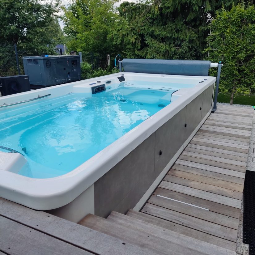 Przydomowy basen typu swim spa z systemem przykrycia na drewnianym tarasie.